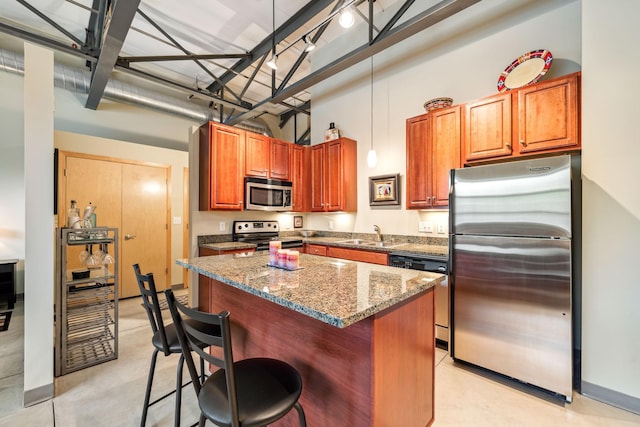 kitchen featuring sink, stone countertops, a center island, stainless steel appliances, and a breakfast bar area