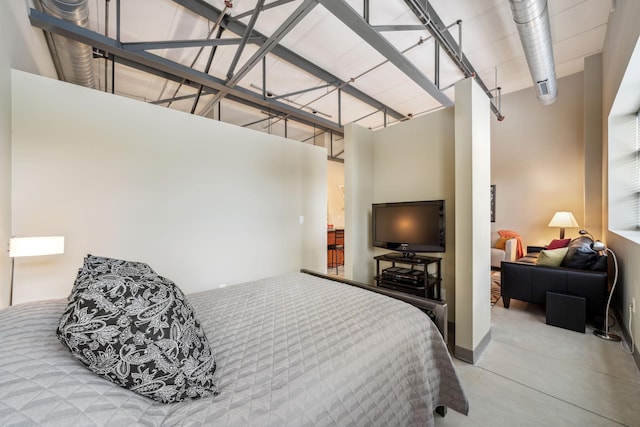 bedroom featuring concrete floors and a towering ceiling