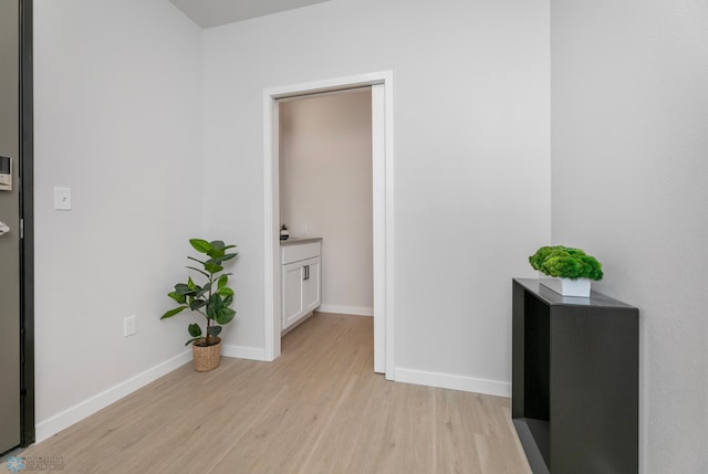 hall with light wood-type flooring and baseboards