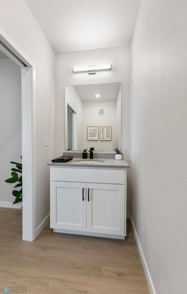 bathroom featuring vanity, baseboards, and wood finished floors