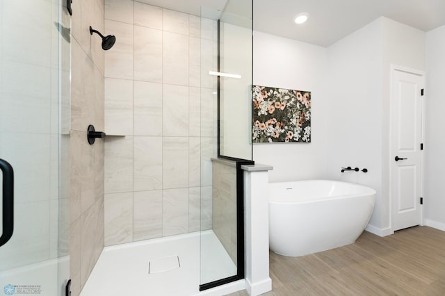 bathroom with a freestanding tub, wood finished floors, and a stall shower