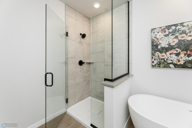 full bathroom featuring baseboards, a freestanding bath, and a shower stall