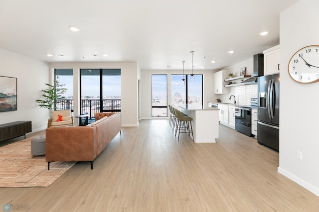 living area with recessed lighting, baseboards, and light wood-style flooring