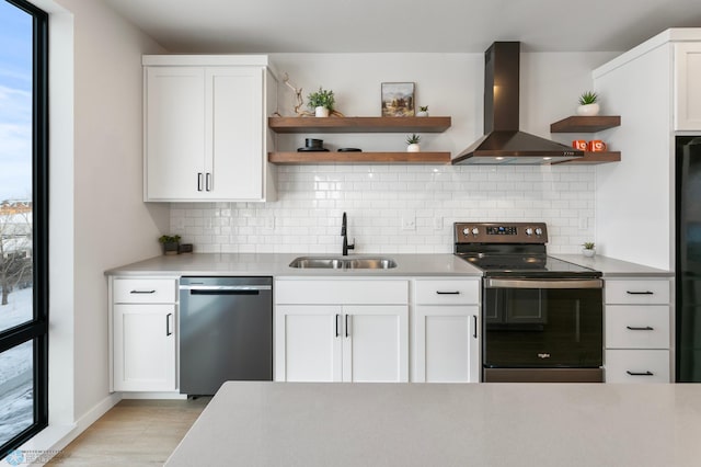 kitchen with open shelves, light countertops, stainless steel appliances, wall chimney exhaust hood, and a sink
