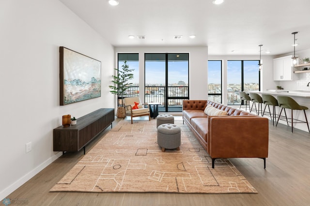 living area with recessed lighting, visible vents, baseboards, and light wood-style floors