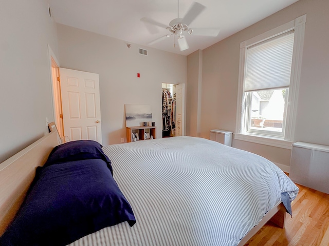 bedroom with ceiling fan, light hardwood / wood-style floors, and a spacious closet