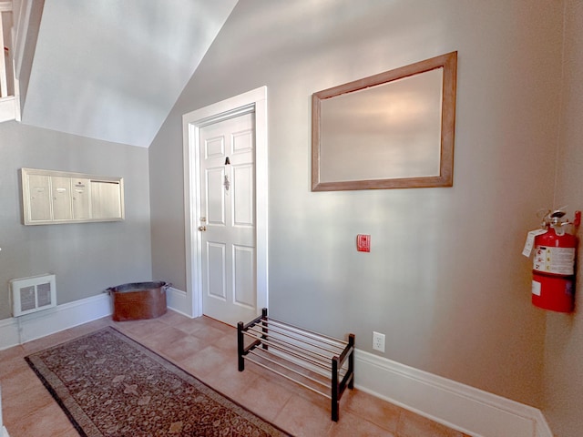 entryway featuring a mail area, light tile patterned floors, and lofted ceiling