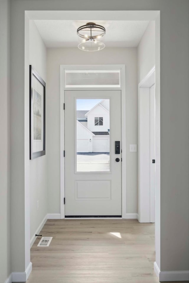 doorway to outside featuring light wood-type flooring and a chandelier