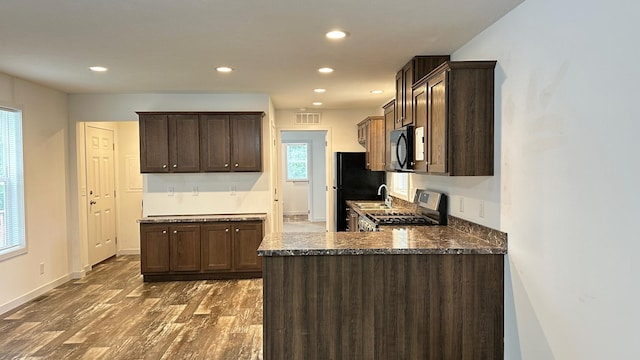 kitchen featuring dark brown cabinets, dark stone countertops, dark hardwood / wood-style flooring, and sink