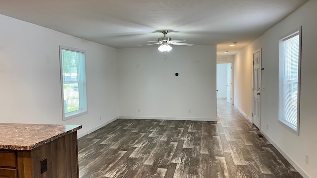 spare room with dark wood-type flooring, ceiling fan, and a wealth of natural light