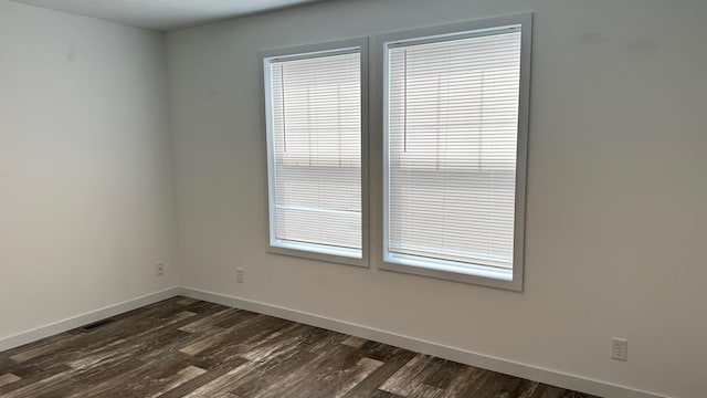 unfurnished room featuring dark wood-type flooring and a healthy amount of sunlight