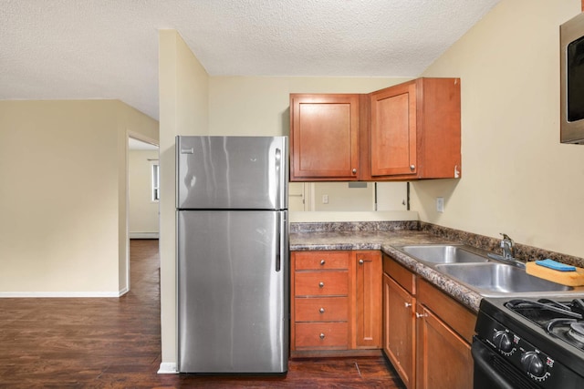 kitchen with appliances with stainless steel finishes, a baseboard radiator, sink, a textured ceiling, and dark wood-type flooring