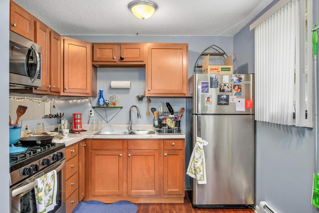 kitchen with a textured ceiling, stainless steel appliances, sink, and dark hardwood / wood-style floors