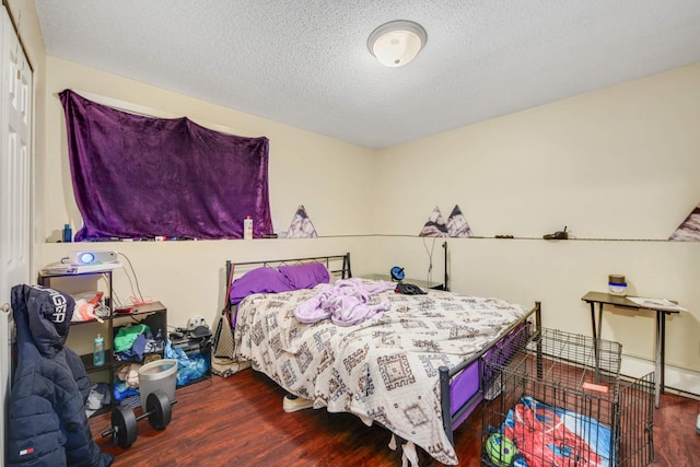 bedroom featuring a textured ceiling and dark hardwood / wood-style floors