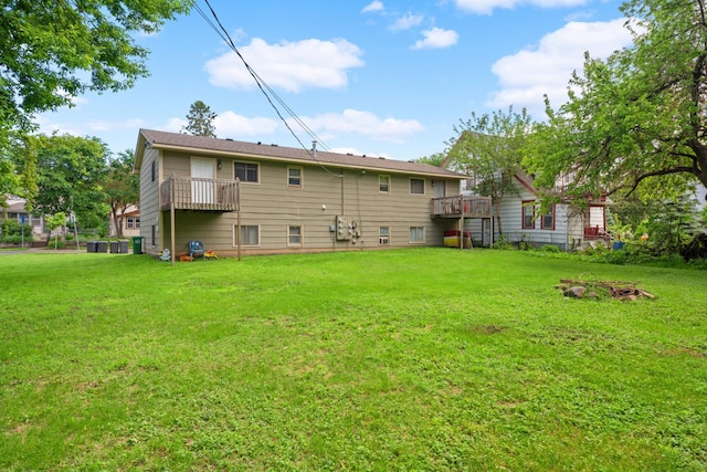 rear view of property featuring a wooden deck and a lawn