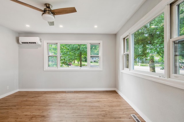 unfurnished room featuring ceiling fan, light hardwood / wood-style floors, and a wall unit AC