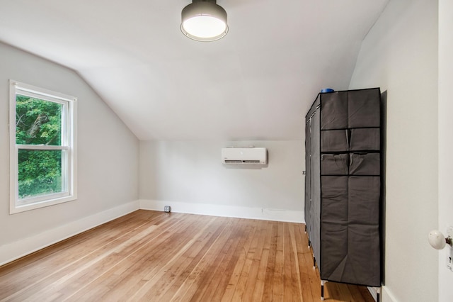 bonus room featuring lofted ceiling, an AC wall unit, and light hardwood / wood-style flooring