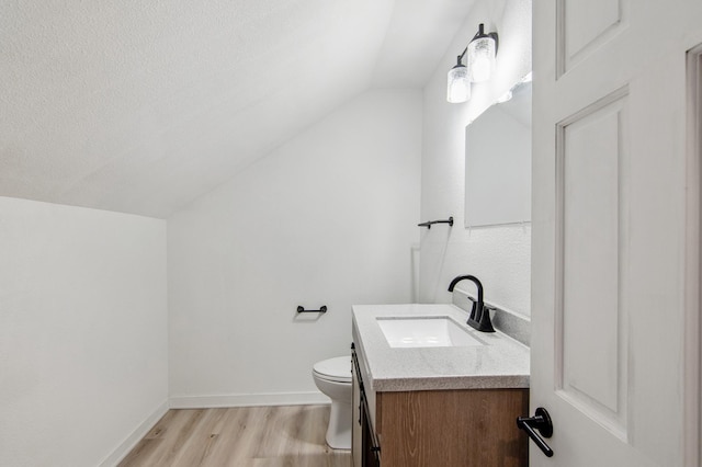 bathroom with vanity, a textured ceiling, lofted ceiling, hardwood / wood-style flooring, and toilet