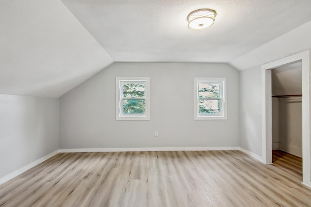 bonus room featuring a textured ceiling, light hardwood / wood-style flooring, plenty of natural light, and vaulted ceiling