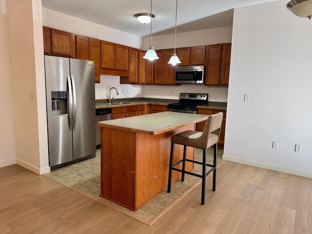 kitchen featuring stainless steel appliances, light wood-style floors, a sink, and a breakfast bar