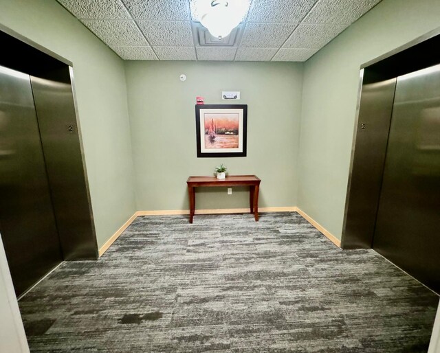 hall featuring baseboards, elevator, and carpet