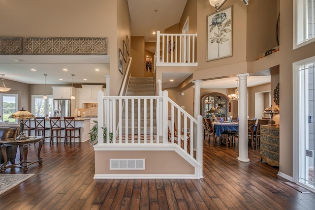 stairs featuring hardwood / wood-style flooring, a high ceiling, and ornate columns