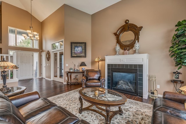 living room featuring an inviting chandelier, dark hardwood / wood-style floors, high vaulted ceiling, and a tile fireplace