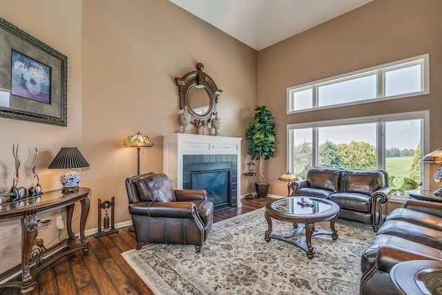 living room featuring a towering ceiling, a tile fireplace, and dark hardwood / wood-style flooring