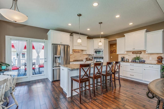 kitchen featuring light stone counters, white cabinetry, appliances with stainless steel finishes, decorative light fixtures, and dark hardwood / wood-style flooring