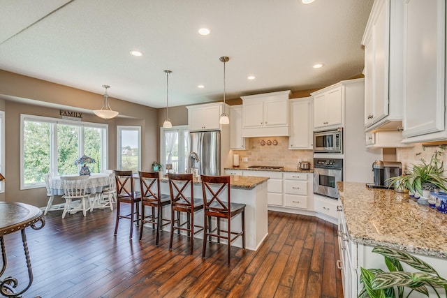 kitchen featuring an island with sink, white cabinets, appliances with stainless steel finishes, and dark hardwood / wood-style floors