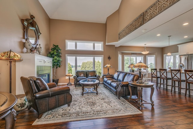 living room featuring a towering ceiling, a tiled fireplace, and dark hardwood / wood-style flooring