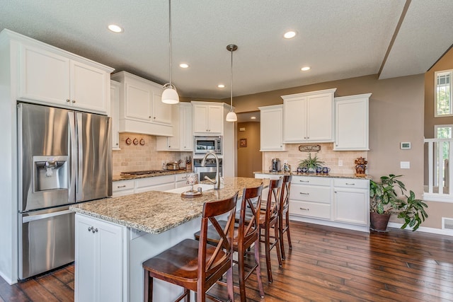 kitchen featuring a center island with sink, appliances with stainless steel finishes, dark hardwood / wood-style floors, and white cabinetry