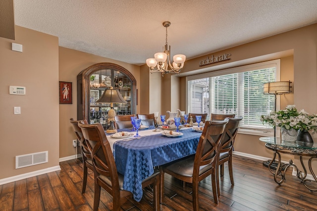 dining area featuring an inviting chandelier, a textured ceiling, and dark wood-type flooring