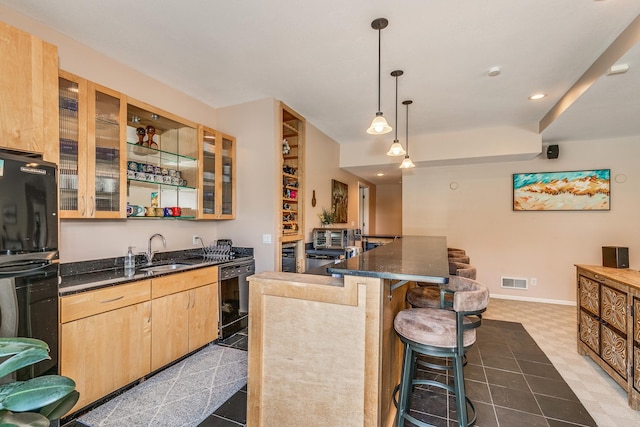 kitchen featuring sink, a kitchen breakfast bar, black appliances, decorative light fixtures, and light brown cabinetry