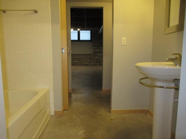 bathroom with concrete floors and washtub / shower combination