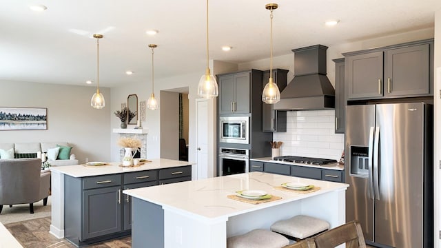 kitchen featuring custom exhaust hood, appliances with stainless steel finishes, a center island, and a breakfast bar