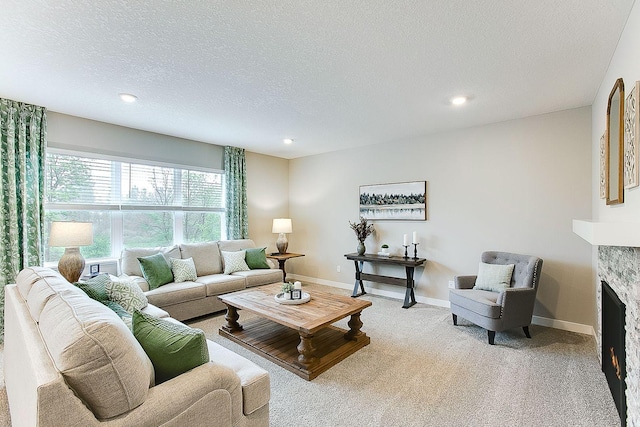 carpeted living room featuring a textured ceiling and a stone fireplace