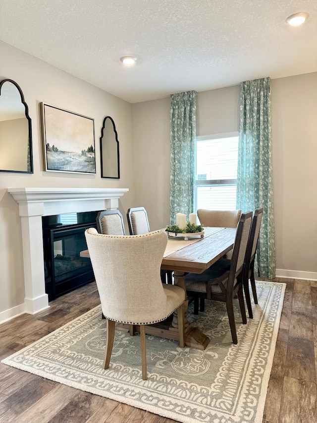 dining area with dark wood-type flooring and a textured ceiling