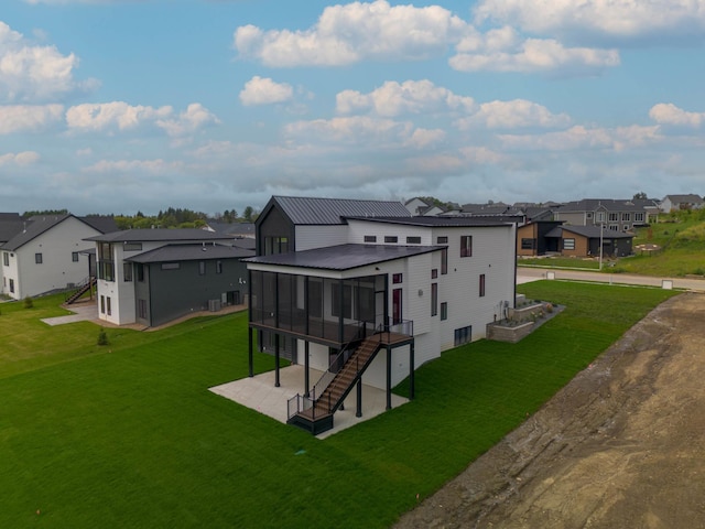 back of house with a patio area, a yard, and a sunroom