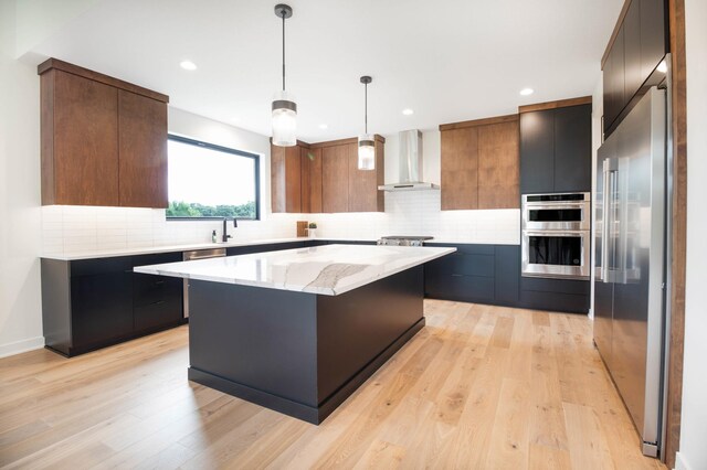 kitchen with wall chimney exhaust hood, decorative backsplash, light hardwood / wood-style flooring, and stainless steel appliances