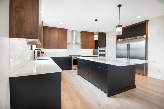 kitchen featuring sink, light hardwood / wood-style floors, decorative backsplash, and wall chimney exhaust hood