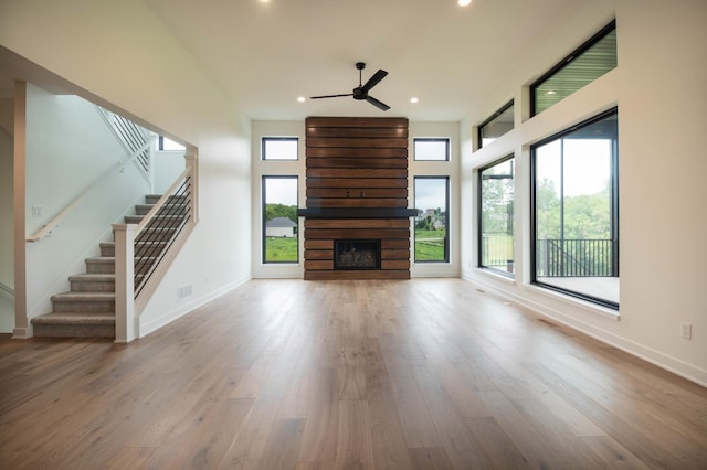 unfurnished living room featuring light wood-type flooring, a large fireplace, and a wealth of natural light