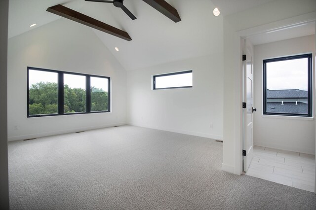 spare room featuring a healthy amount of sunlight, beamed ceiling, and light carpet