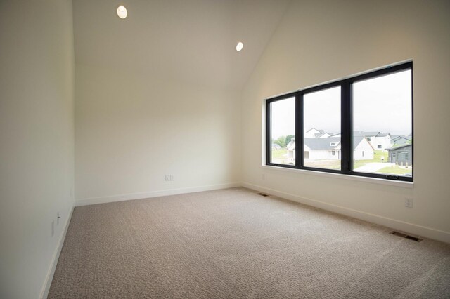 unfurnished room featuring high vaulted ceiling and light colored carpet