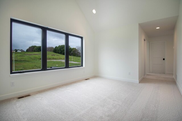 carpeted spare room with high vaulted ceiling