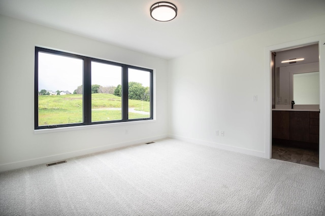 unfurnished bedroom featuring sink, ensuite bathroom, and carpet flooring