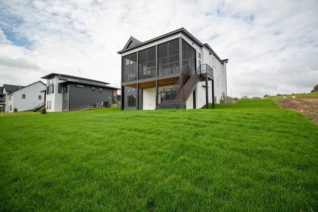 rear view of property featuring a lawn, a sunroom, and central AC