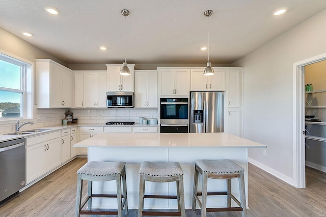 kitchen featuring a kitchen island, white cabinetry, pendant lighting, and appliances with stainless steel finishes