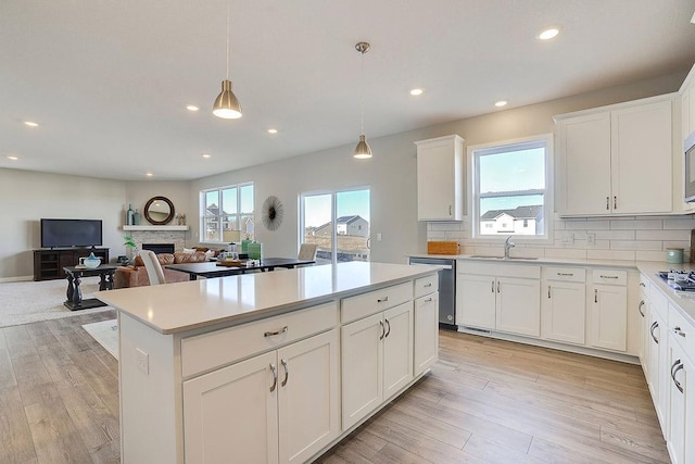 kitchen with pendant lighting, a wealth of natural light, sink, and light wood-type flooring