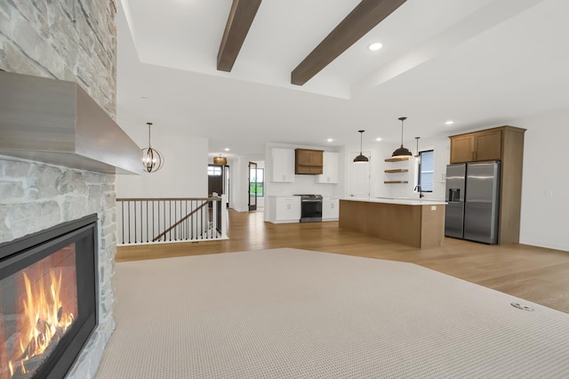 unfurnished living room with beamed ceiling, a healthy amount of sunlight, an inviting chandelier, and light wood-type flooring